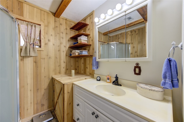 bathroom featuring beam ceiling, vanity, and wooden walls