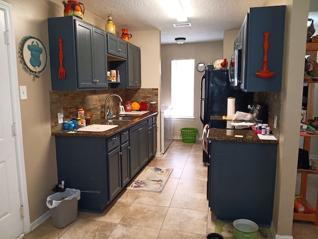 kitchen featuring decorative backsplash, independent washer and dryer, sink, light tile patterned flooring, and a textured ceiling