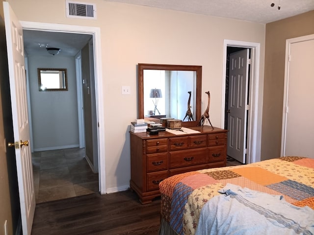 bedroom featuring dark wood-type flooring, a textured ceiling, and multiple windows