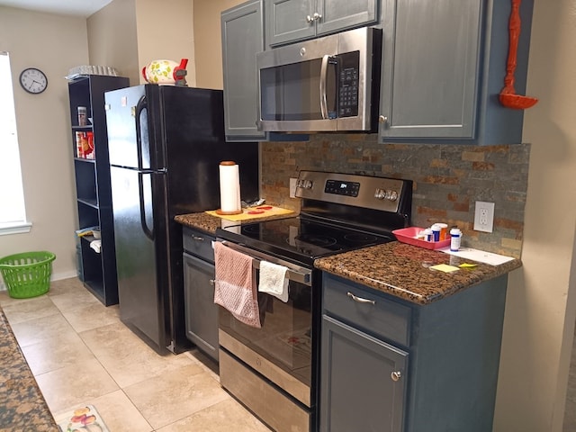 kitchen featuring decorative backsplash, stainless steel appliances, dark stone counters, and gray cabinetry