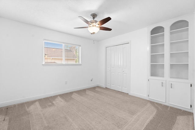 unfurnished bedroom with a closet, a textured ceiling, light colored carpet, and ceiling fan