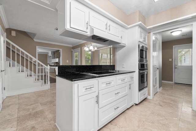 kitchen featuring stovetop, an inviting chandelier, white cabinetry, a textured ceiling, and crown molding