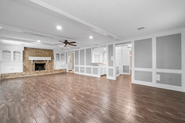 unfurnished living room featuring a fireplace, hardwood / wood-style flooring, crown molding, built in shelves, and ceiling fan