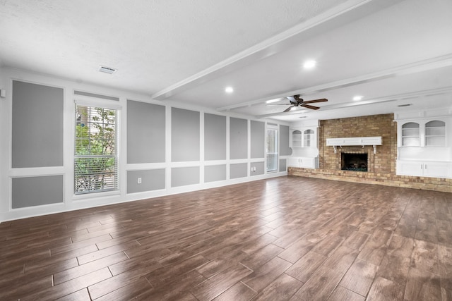 unfurnished living room featuring ceiling fan, a textured ceiling, dark hardwood / wood-style flooring, and a brick fireplace