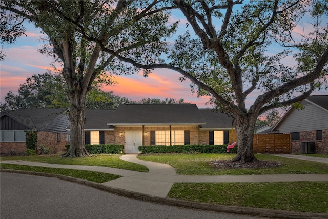 single story home featuring a lawn and central air condition unit