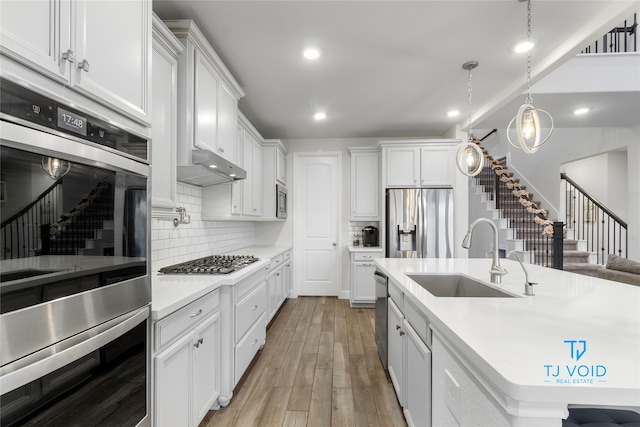 kitchen with light hardwood / wood-style flooring, white cabinets, sink, and stainless steel appliances