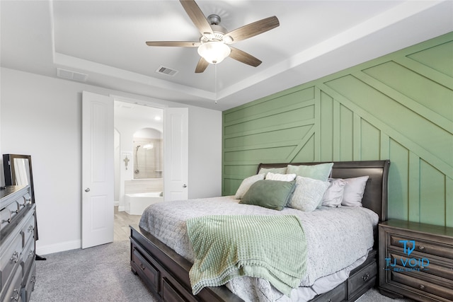 carpeted bedroom featuring ceiling fan, a raised ceiling, and connected bathroom