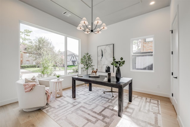 home office with light wood-type flooring and a notable chandelier