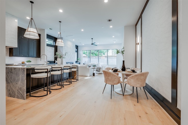 dining space with ceiling fan and light hardwood / wood-style flooring