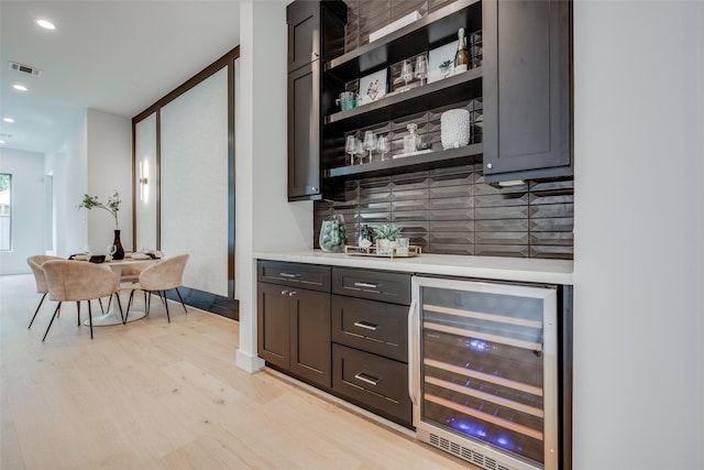 bar featuring light hardwood / wood-style floors, wine cooler, and tasteful backsplash