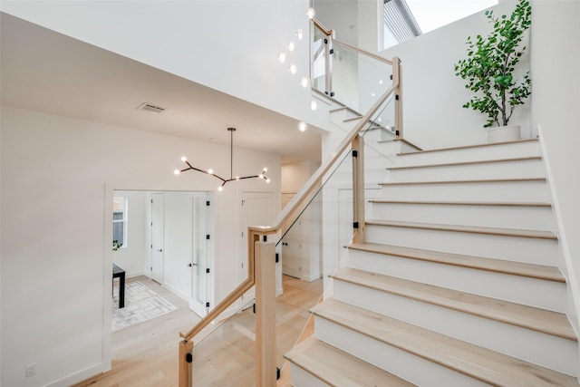 stairs featuring hardwood / wood-style floors and an inviting chandelier