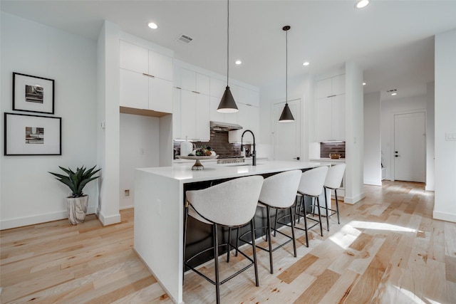 kitchen featuring visible vents, a kitchen breakfast bar, white cabinets, modern cabinets, and a sink