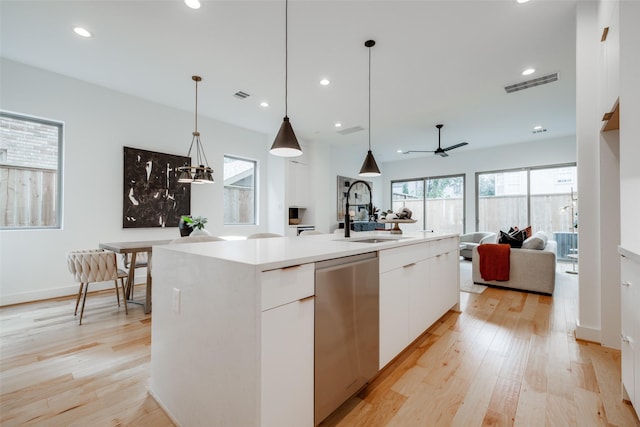 kitchen featuring visible vents, a sink, open floor plan, light wood-style floors, and dishwasher