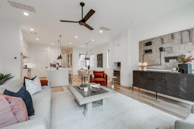 living area featuring recessed lighting, visible vents, wine cooler, and light wood finished floors