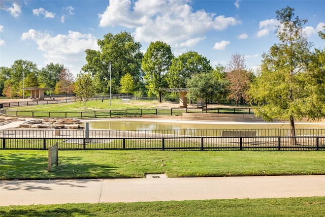 view of community featuring a lawn, fence, and a water view