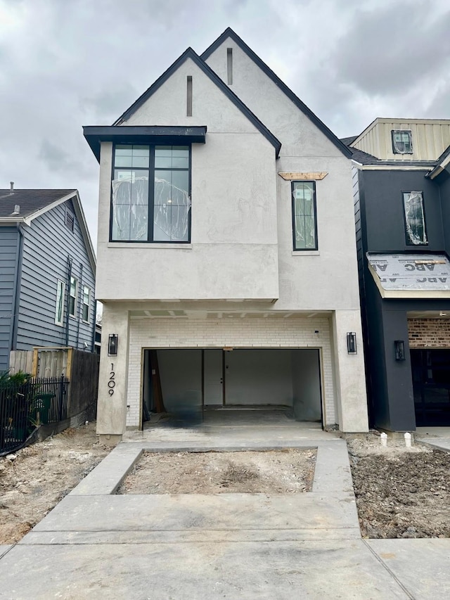 view of front of house with a garage, fence, brick siding, and stucco siding