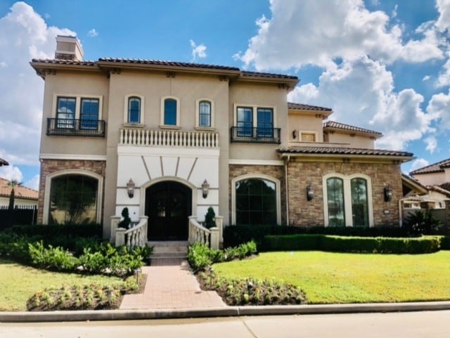 mediterranean / spanish house with a balcony and a front lawn