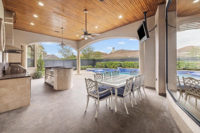 view of patio with ceiling fan, a fenced in pool, and an outdoor kitchen