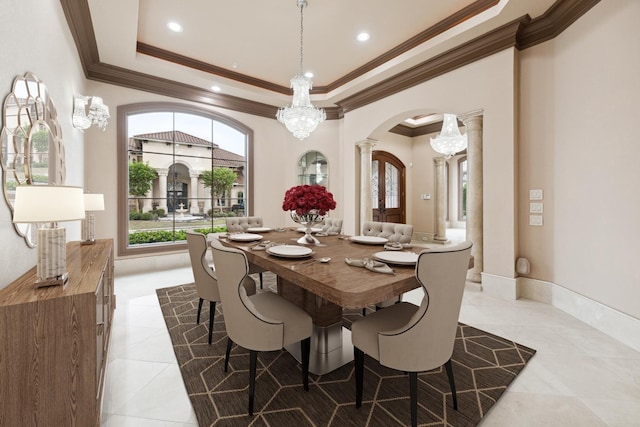 tiled dining area with a raised ceiling, crown molding, a chandelier, and decorative columns