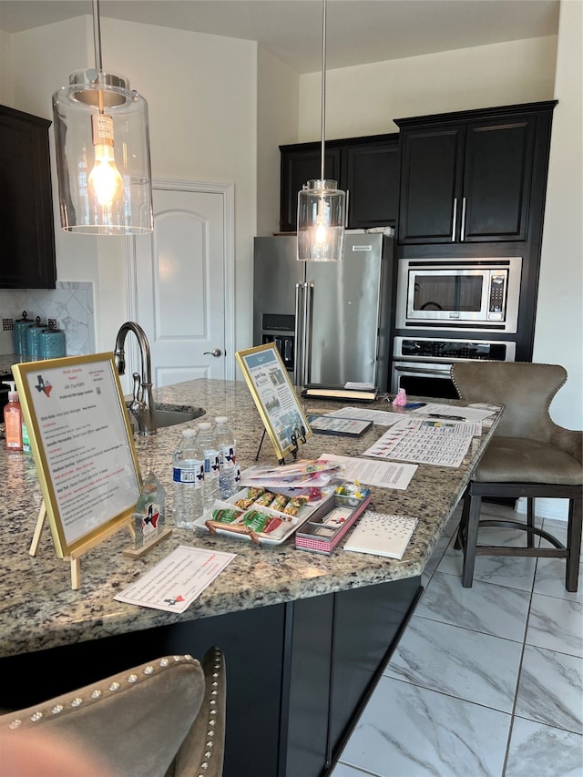 kitchen with decorative backsplash, pendant lighting, appliances with stainless steel finishes, and sink