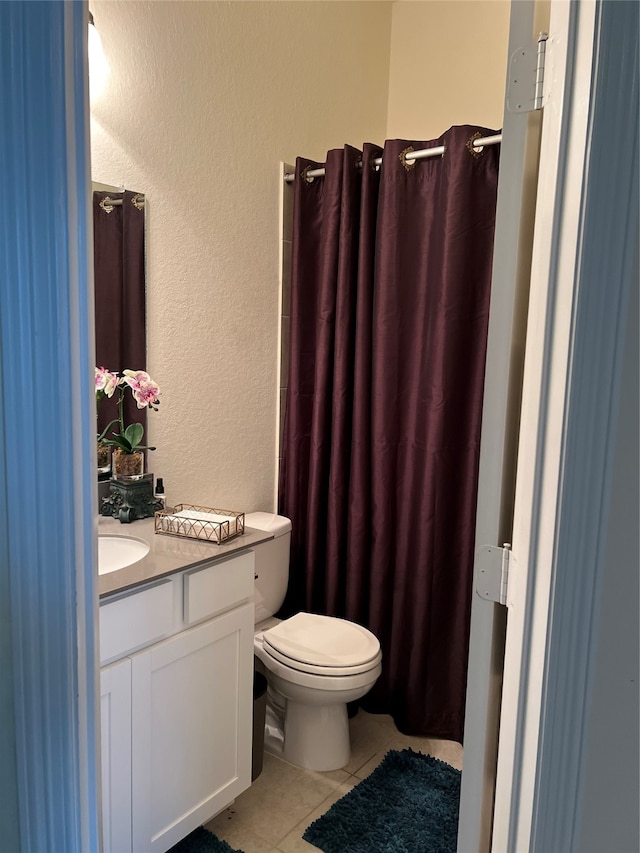 bathroom with toilet, vanity, and tile patterned floors