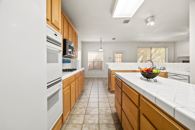 kitchen featuring tile counters, tasteful backsplash, sink, and white appliances