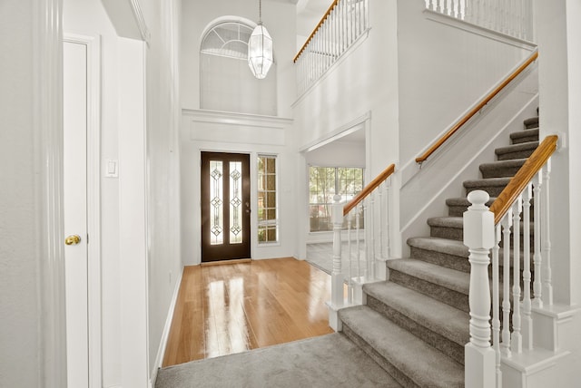 entrance foyer with light hardwood / wood-style flooring and a towering ceiling