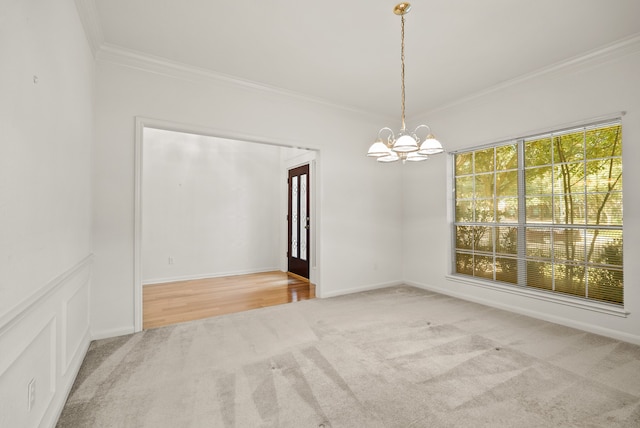 spare room featuring crown molding, carpet floors, and a chandelier