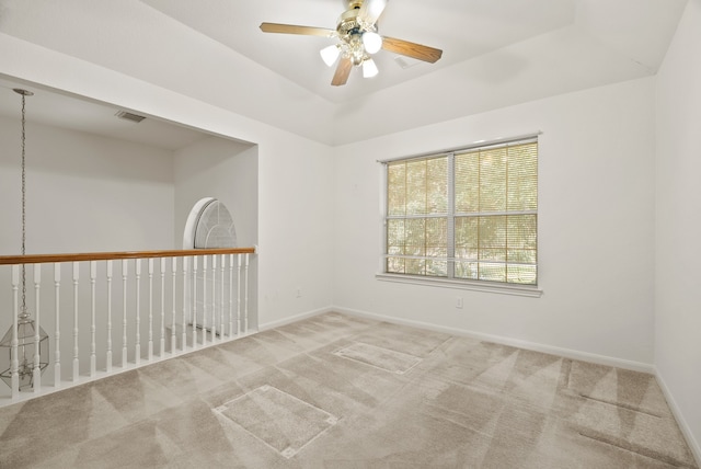 empty room featuring carpet floors, a tray ceiling, and ceiling fan