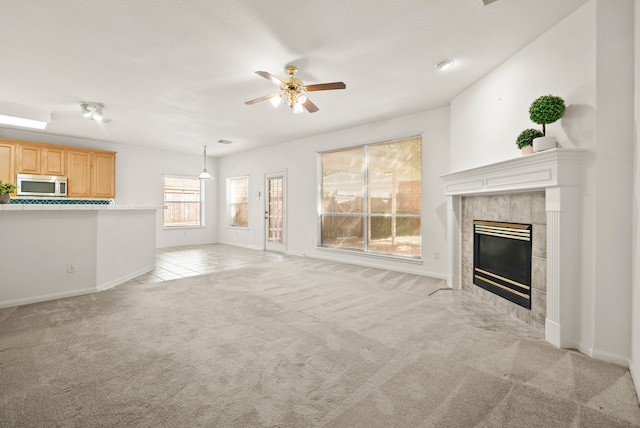 unfurnished living room featuring light colored carpet, a tile fireplace, and ceiling fan