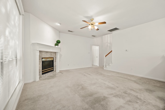 unfurnished living room with ceiling fan, a fireplace, and light colored carpet