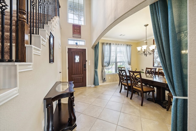 tiled entryway with an inviting chandelier and ornamental molding