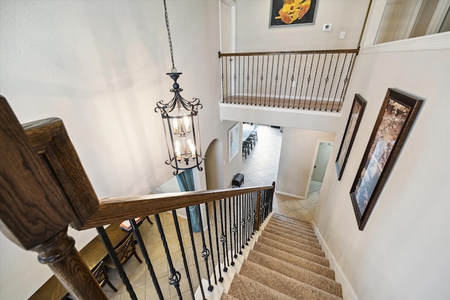 staircase featuring a chandelier, a high ceiling, and tile patterned flooring