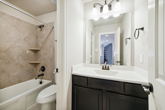 full bathroom featuring vanity, tiled shower / bath combo, and toilet