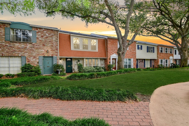 view of property featuring brick siding and a front lawn