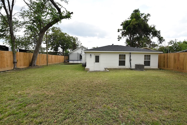 rear view of property with central AC and a lawn