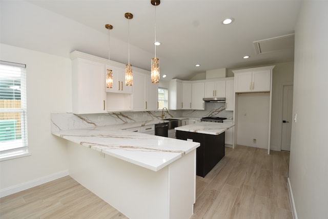 kitchen featuring a kitchen island, pendant lighting, white cabinets, light stone counters, and light hardwood / wood-style floors