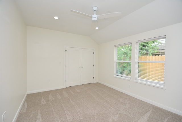 spare room with ceiling fan, light colored carpet, and vaulted ceiling