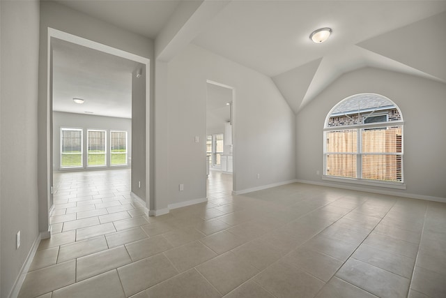 tiled empty room featuring vaulted ceiling