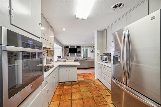 kitchen with white cabinetry, kitchen peninsula, decorative backsplash, and stainless steel appliances