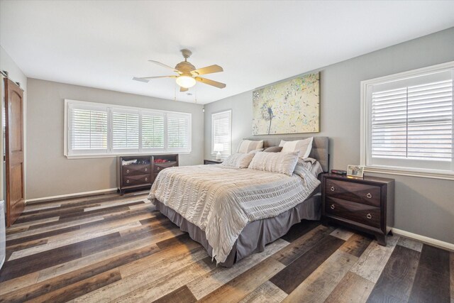 bedroom with multiple windows, dark hardwood / wood-style floors, and ceiling fan