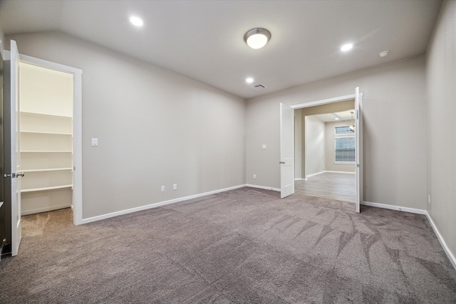 carpeted empty room featuring vaulted ceiling