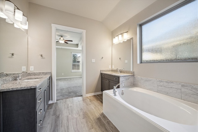 bathroom with a bathing tub, lofted ceiling, ceiling fan, hardwood / wood-style flooring, and vanity