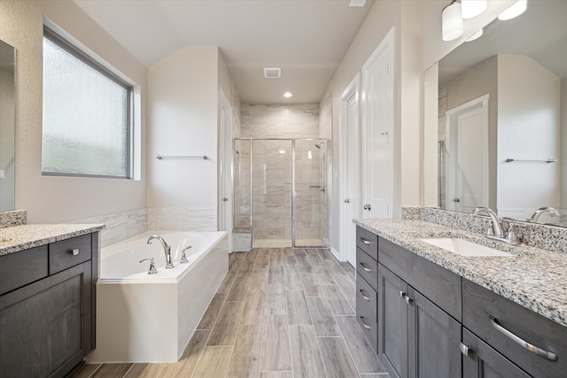 bathroom with vanity, hardwood / wood-style flooring, separate shower and tub, and vaulted ceiling