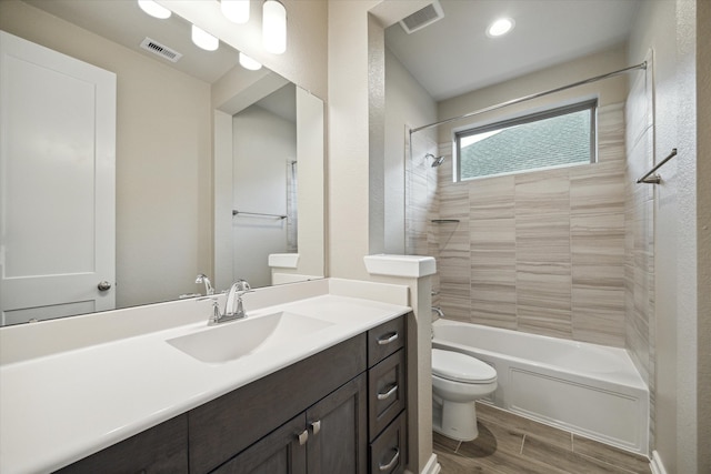 full bathroom with vanity, tiled shower / bath combo, wood-type flooring, and toilet