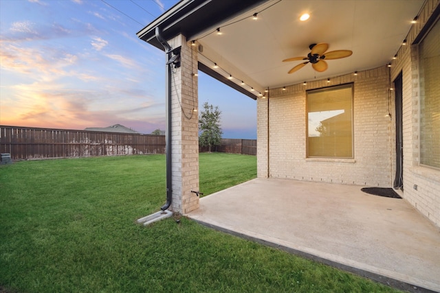 yard at dusk with a patio area and ceiling fan