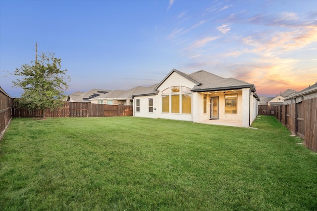 back house at dusk featuring a yard