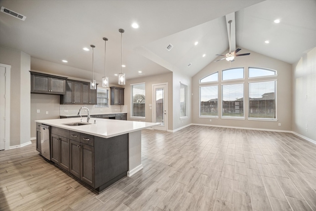 kitchen with sink, hanging light fixtures, light hardwood / wood-style floors, stainless steel dishwasher, and a center island with sink