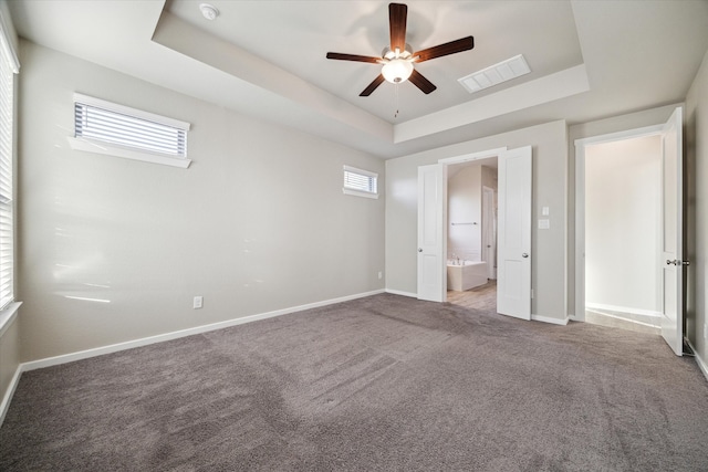 unfurnished bedroom with ceiling fan, multiple windows, and a raised ceiling