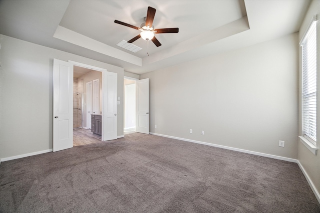 unfurnished bedroom featuring carpet flooring, a tray ceiling, and ceiling fan